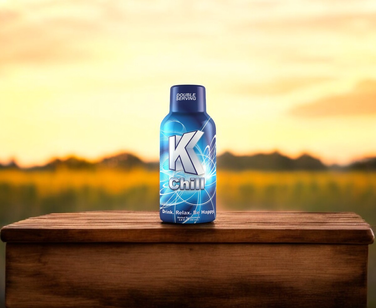 A K Chill 2oz Shot bottle rests gracefully on a wooden surface, set against the backdrop of a blurred outdoor landscape.
