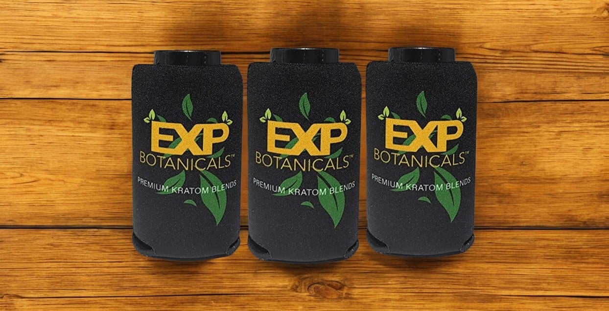 Three black EXP Collapsible Koozies with green leaf designs and "Premium Kratom Blend" text stand on a wooden surface.