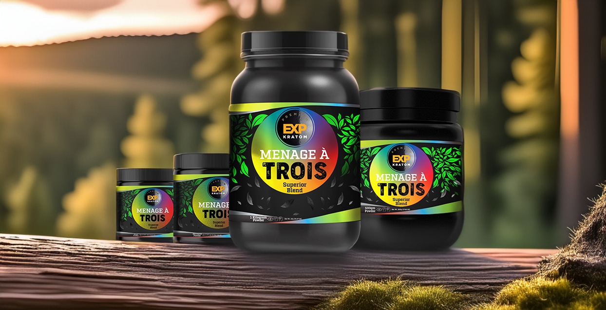 Four jars of New EXP Premium Menage A Trois Powder are displayed on a wooden surface outdoors, with a blurred forest background, highlighting the fine quality of the powder inside.