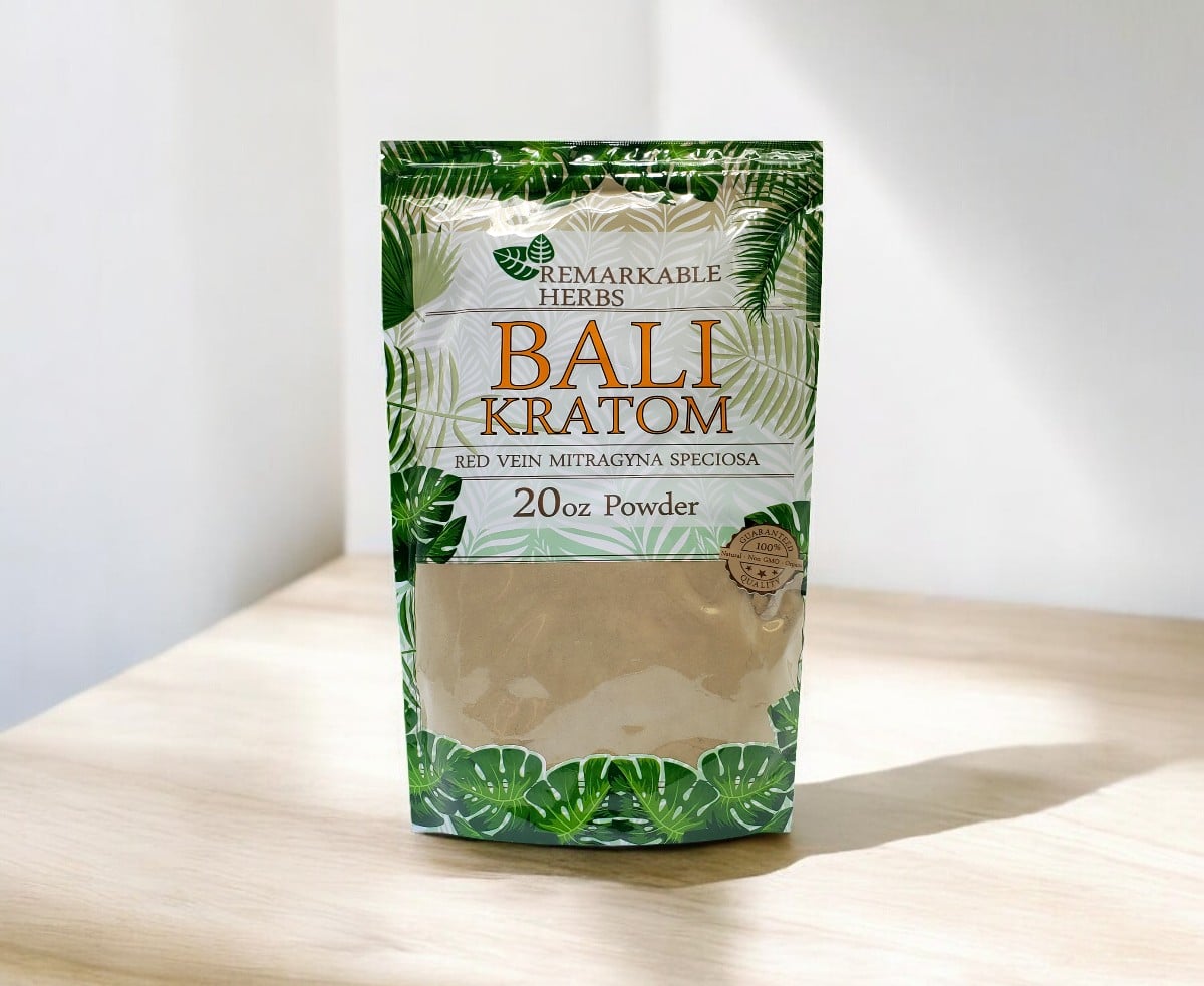 A 20 oz package of Remarkable Herbs Red Bali Kratom Powder is artfully placed on a light wooden surface against a neutral background, showcasing the quality of Remarkable Herbs.